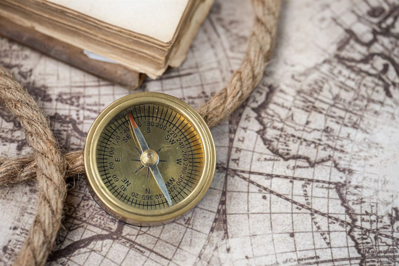 A vintage navigational compass resting on an antique chart